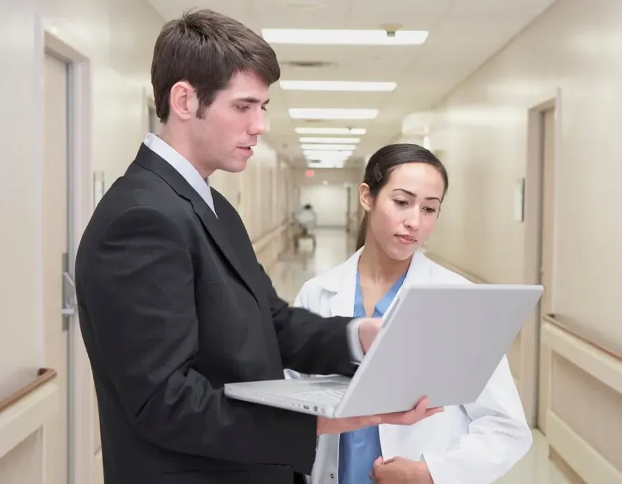 Healthcare manager reviewing documents with nurse administrator in hospital hallway